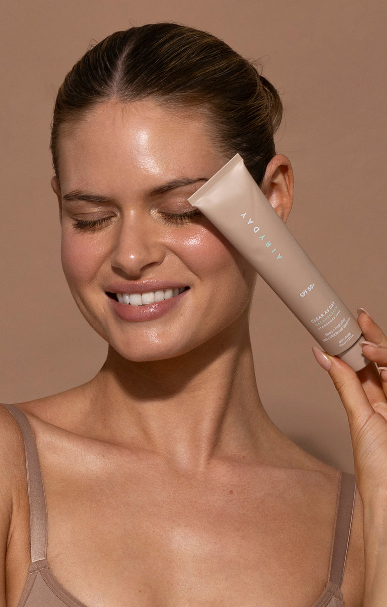 Woman holding Clear As Day Fragrance Free tube with a neutral background