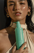 Model holding a teal bottle of Airyday Tough Luxe SPF50